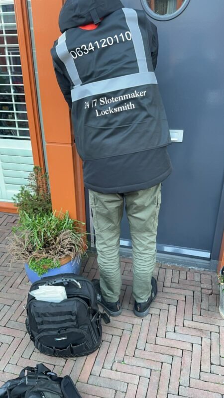 Een slotenmaker opent schadevrij een voordeur in een woonwijk in Amsterdam.