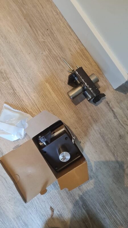 Sleutels en cilinderslot liggen op een houten vloer naast een leren sleutelhoesje